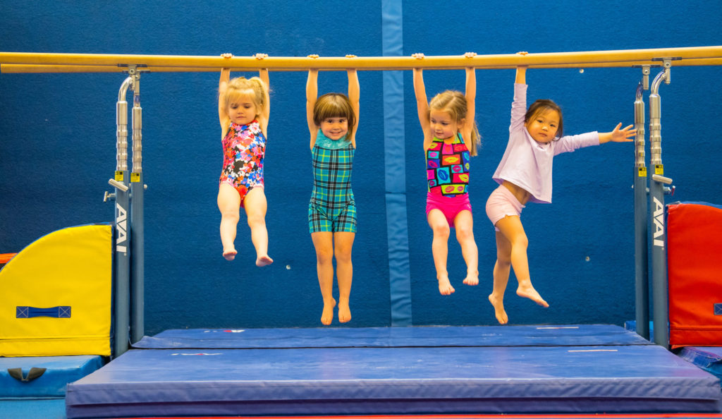 Children hanging on to a bar